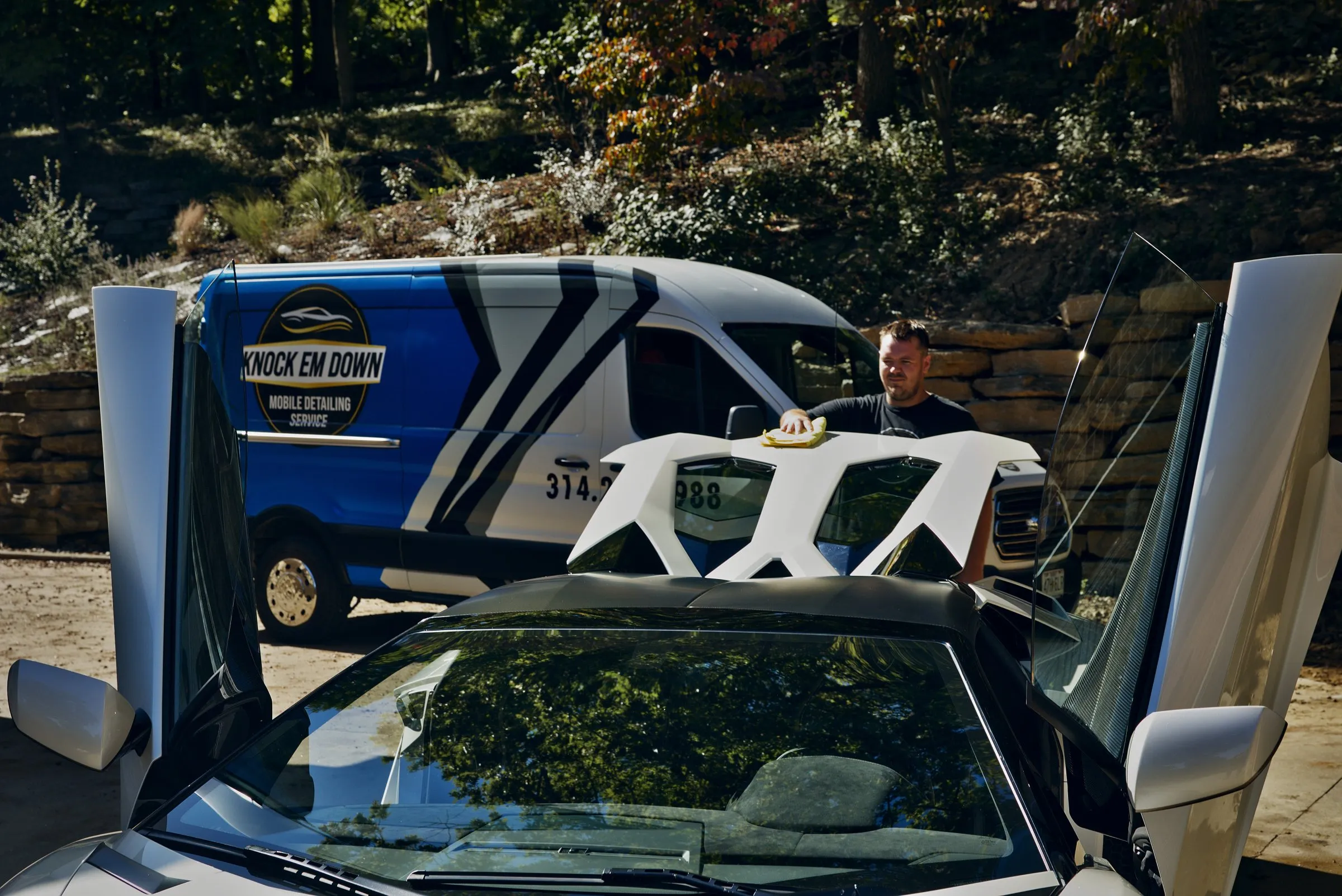 Wiping down a white Lamborghini Aventador, doors up, with the Knock Em Down van behind
