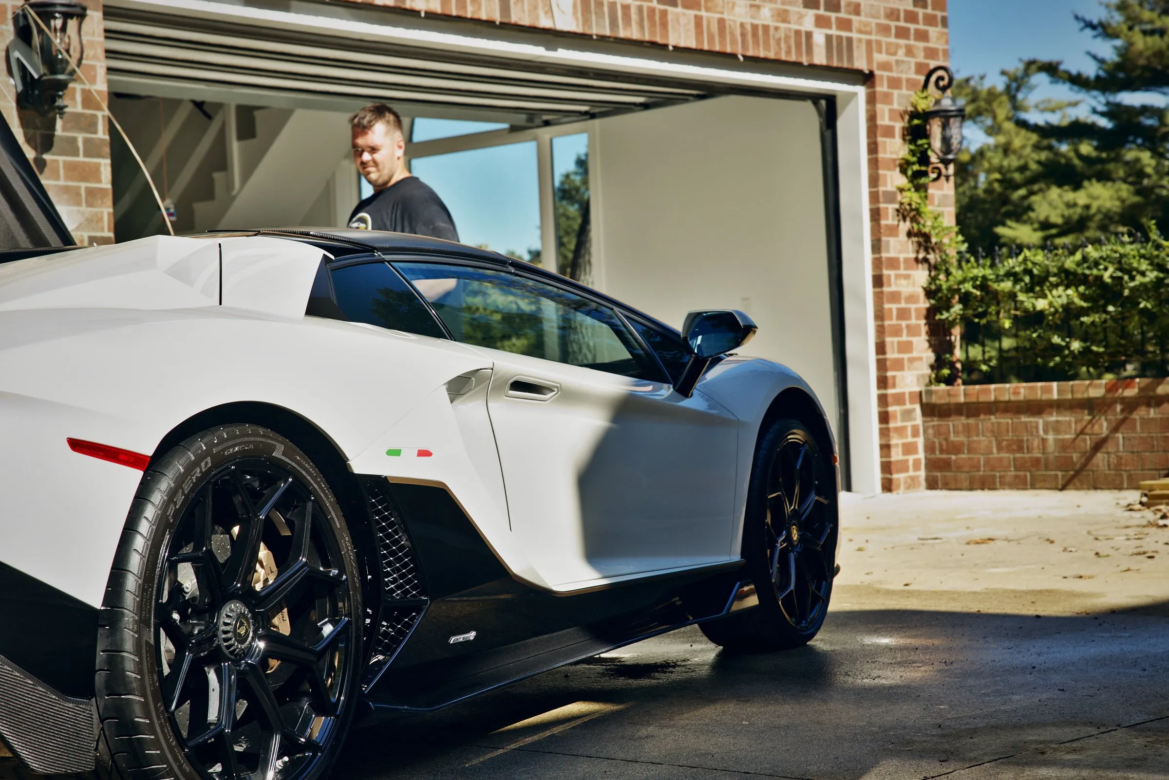 Low view of a white Lamborghini Aventador’s black wheel and side intake after a detail