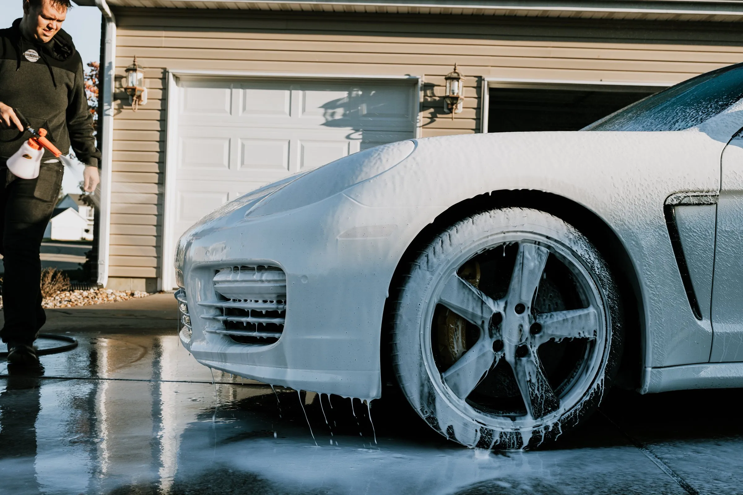 White Porsche Panamera under a full coat of foam during the contact wash