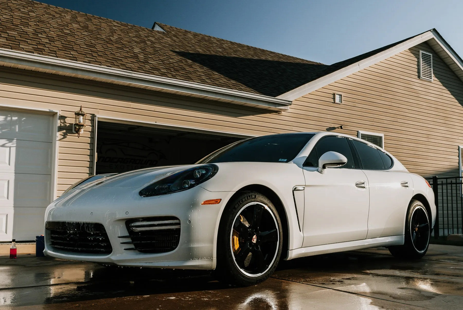A finished white Porsche Panamera parked in a driveway after detailing