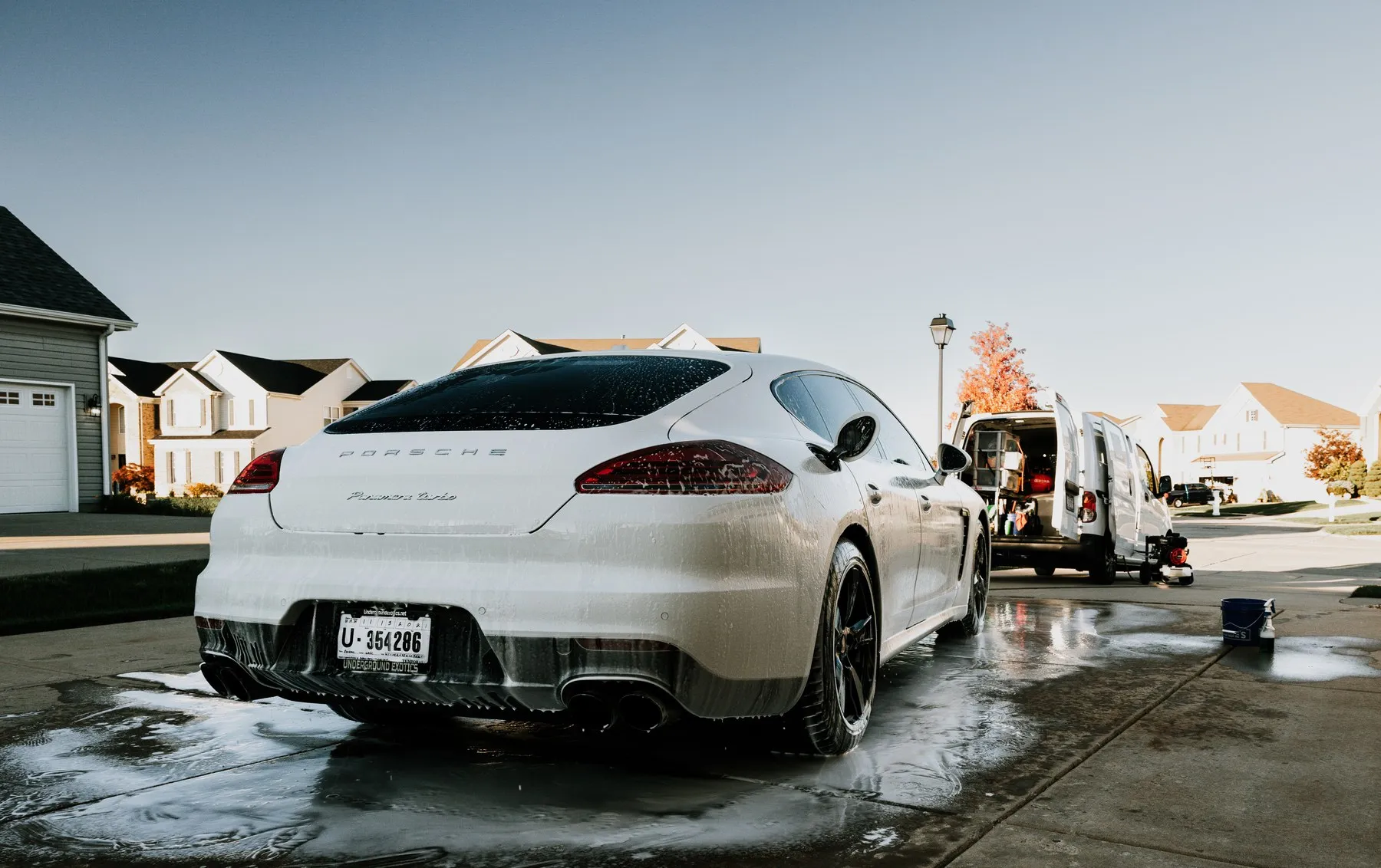 The Knock Em Down van parked on a residential street beside a Porsche Panamera being washed