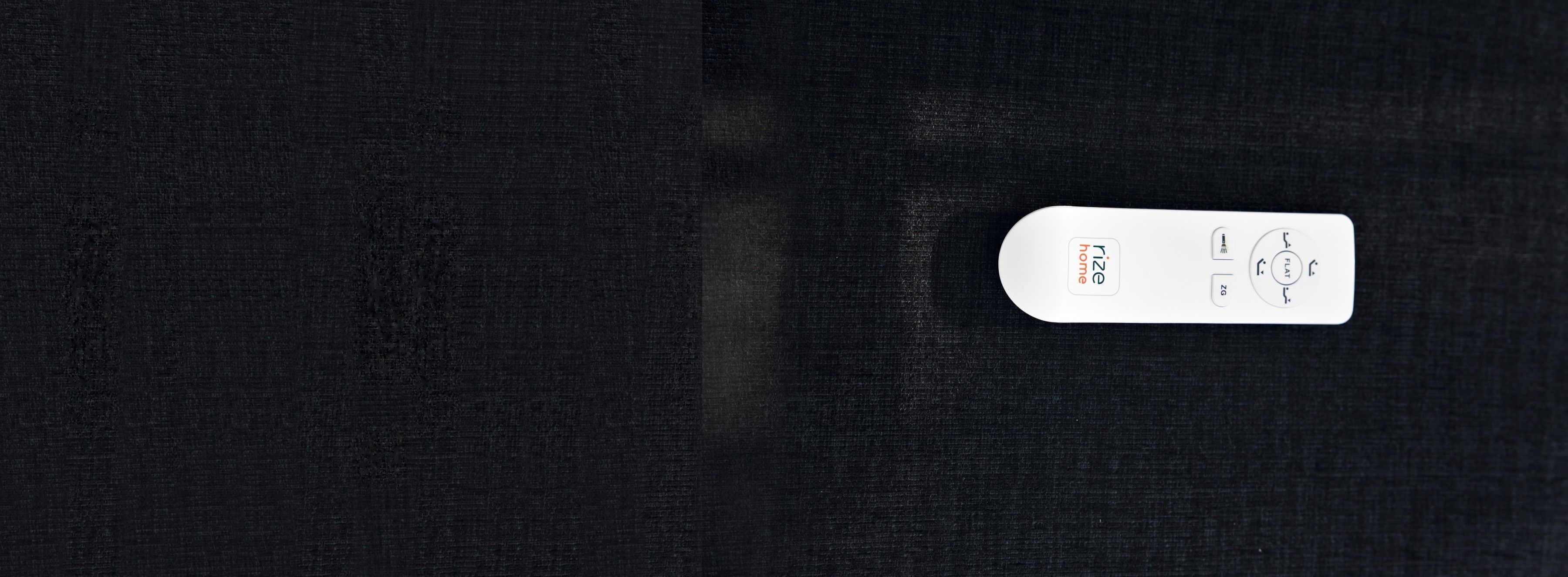 A Rize adjustable-base remote with head, foot, flat and zero-gravity buttons, on dark fabric