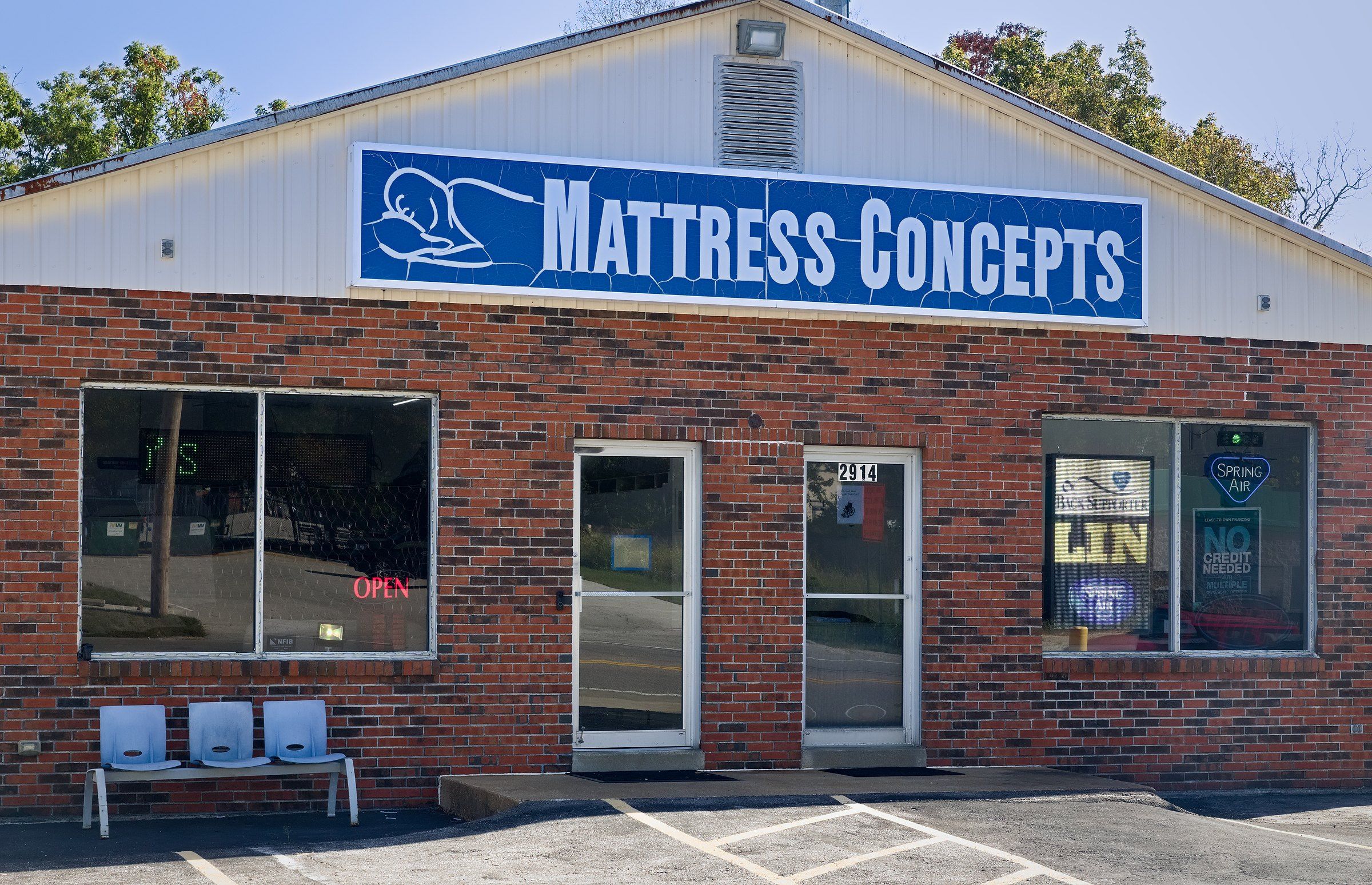 The Mattress Concepts storefront on High Ridge Blvd., with the blue sign over the doors and chairs out front