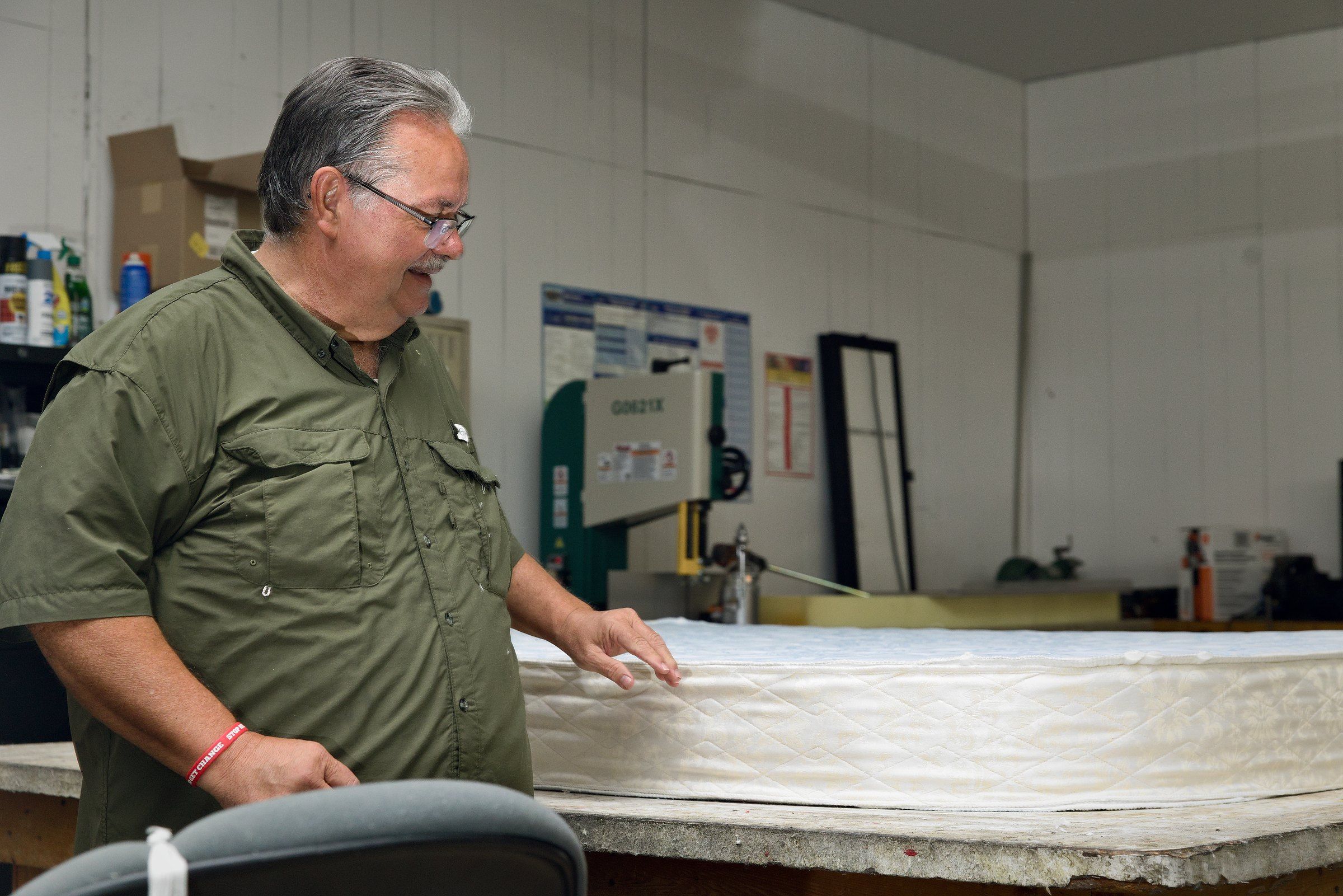 Clinton smiling as he checks a finished mattress on the shop table