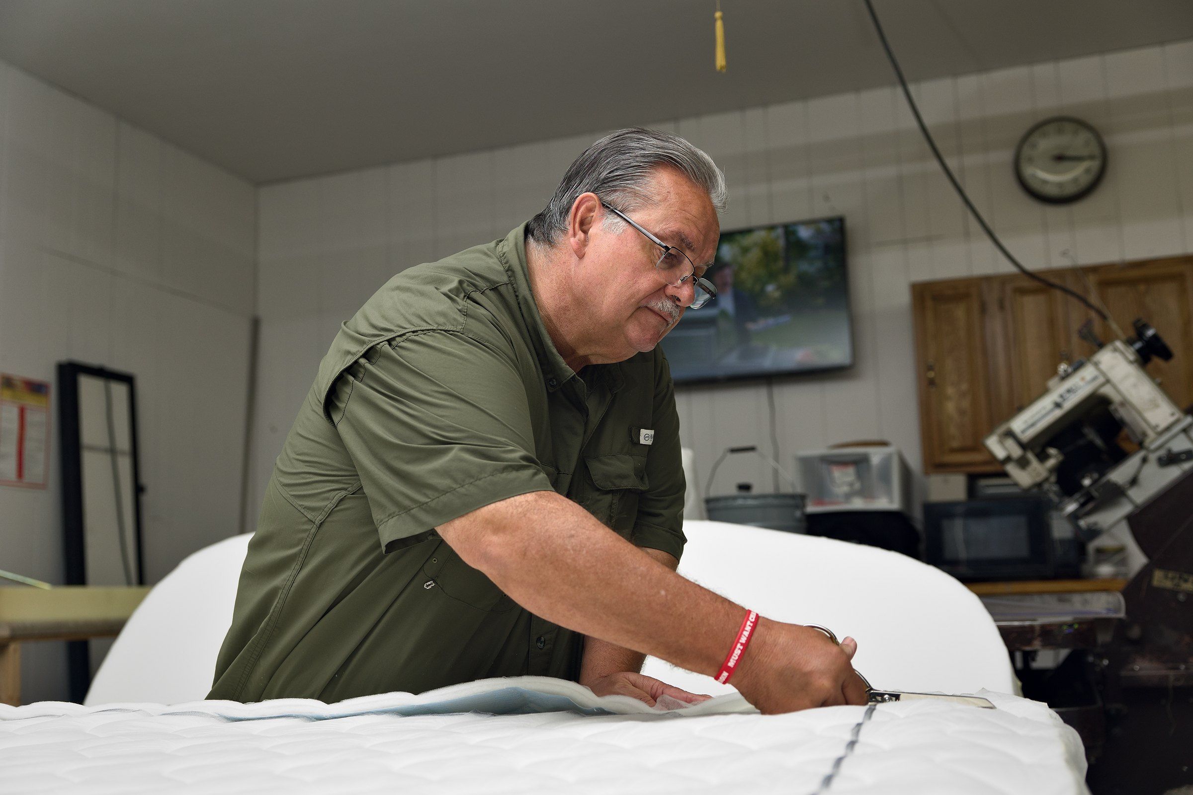 Clinton trimming the quilted border of a mattress in the shop