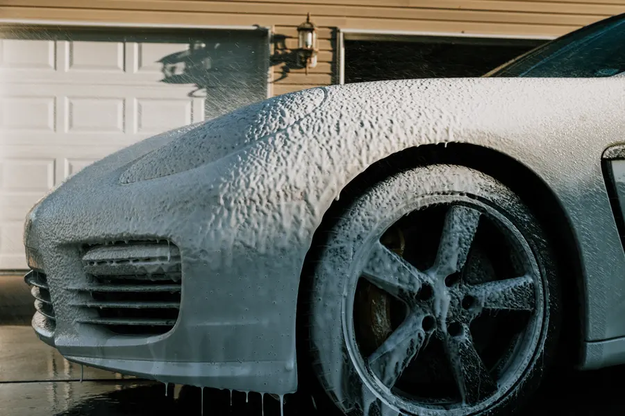 The front quarter of a Panamera under a thick coat of white foam.