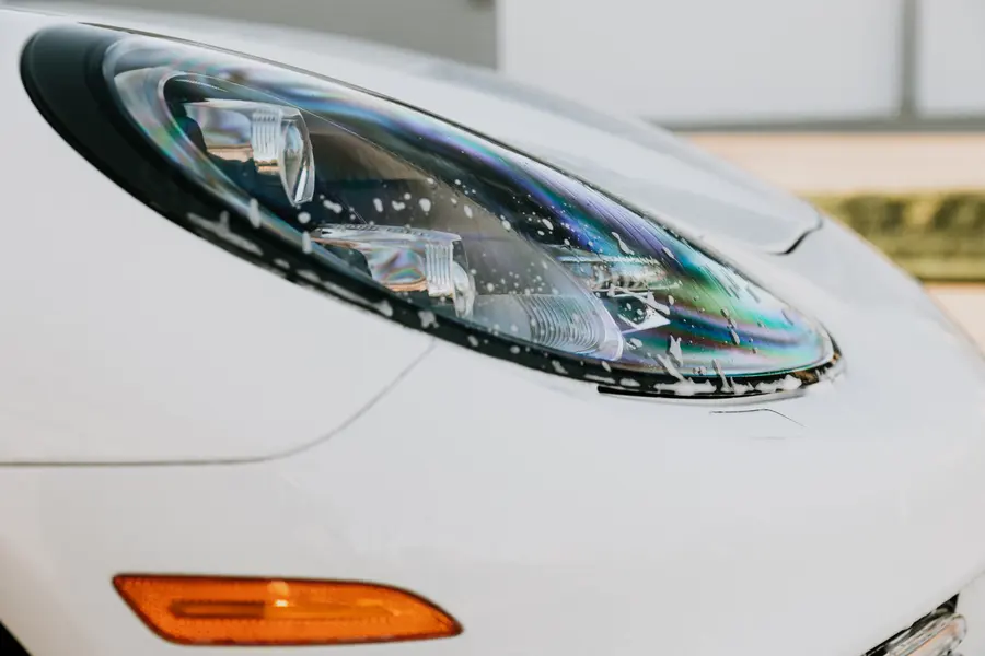 A clean Panamera headlight, the lens catching an iridescent sheen.