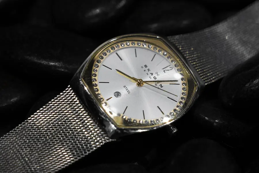 A mesh strap watch resting on dark leather.