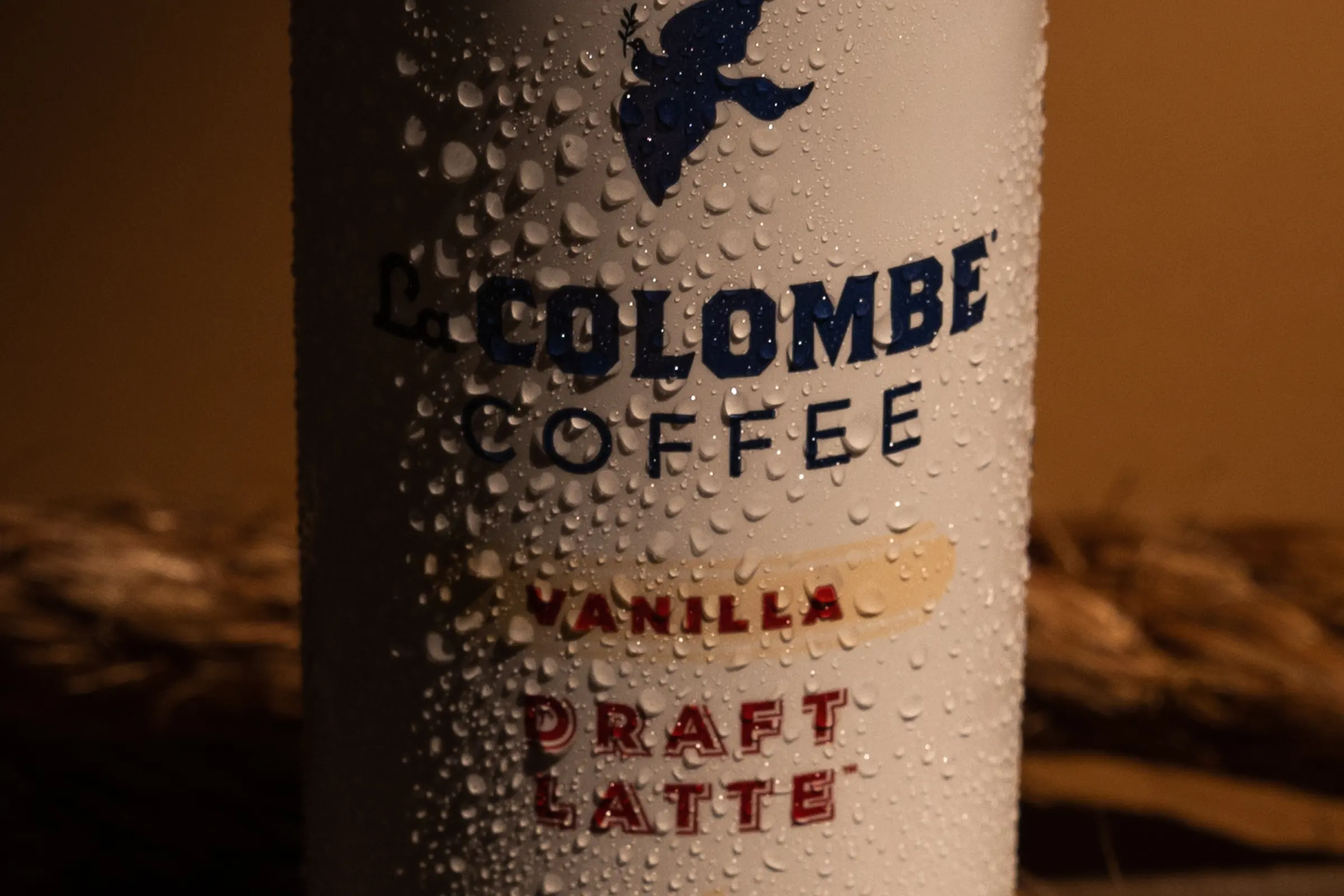 A La Colombe draft latte can standing in warm light on wheat.