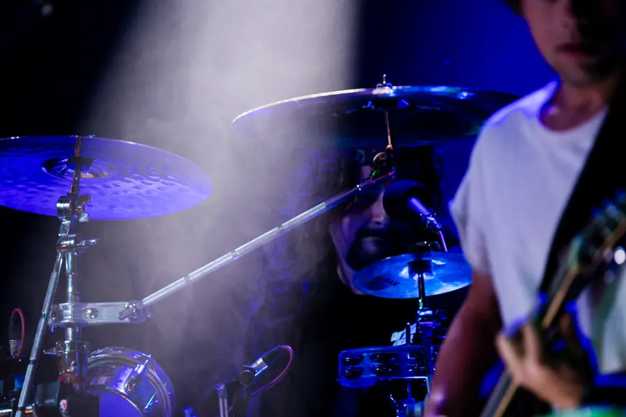 A drummer seen through blue smoke and cymbals.