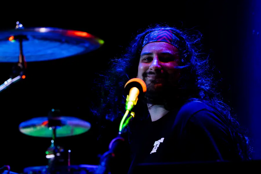 A drummer singing under a green and blue wash.