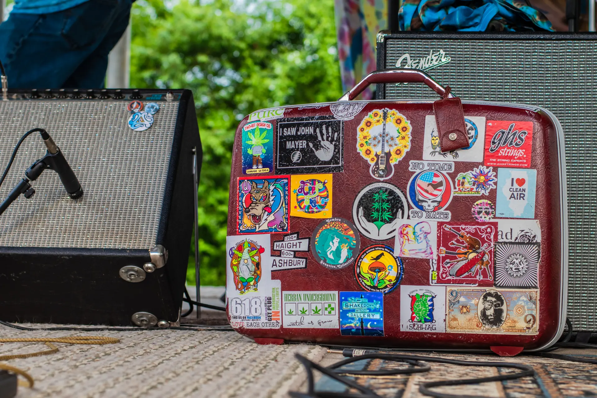 A sticker covered hard case propped against an amplifier.
