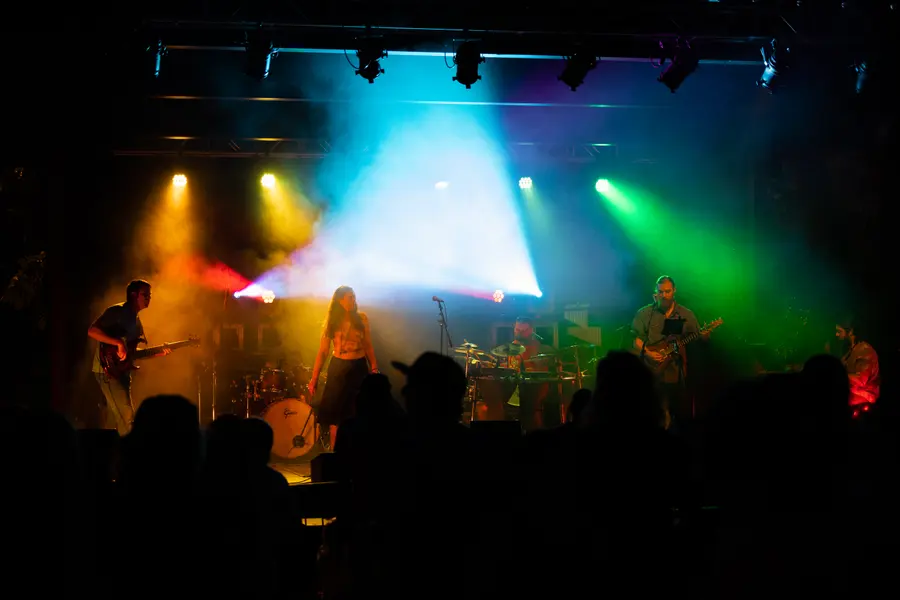 A club stage washed in blue and green beams over a silhouetted crowd.