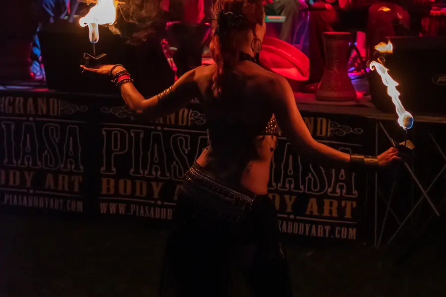 A fire dancer working in front of a festival banner.