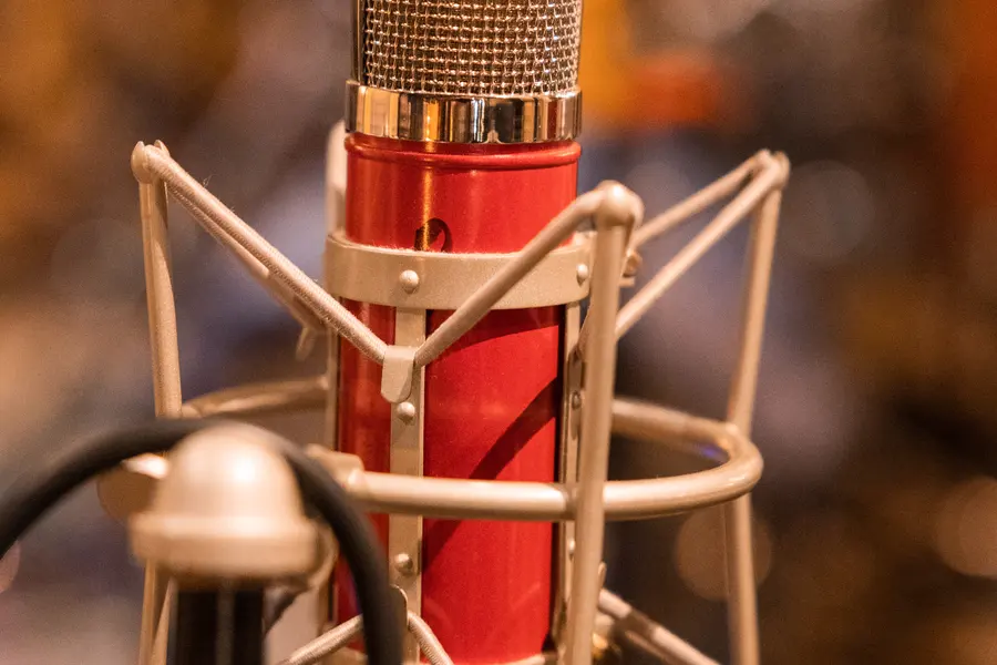 A red condenser microphone in a shock mount, warm light behind.